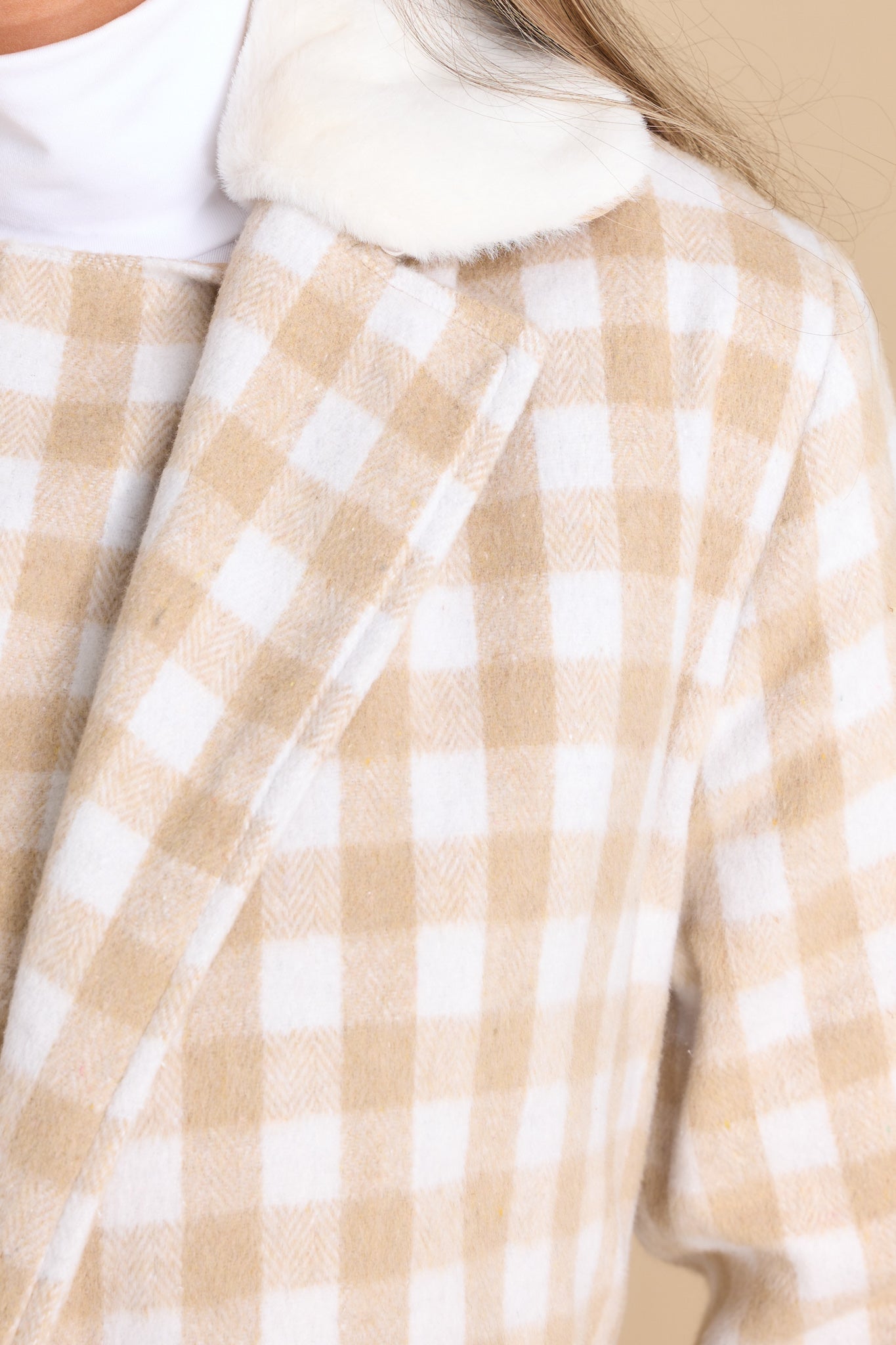 Close up view of this double breasted coat that features an open neckline, removeable faux fur collar, a self-tie fabric belt around the waist, and functional waist pockets.