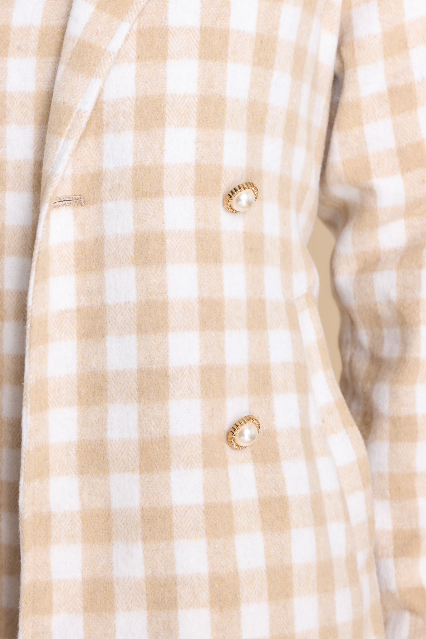 Close up view of this double breasted coat that features gold and pearl buttons on the front and functional waist pockets.