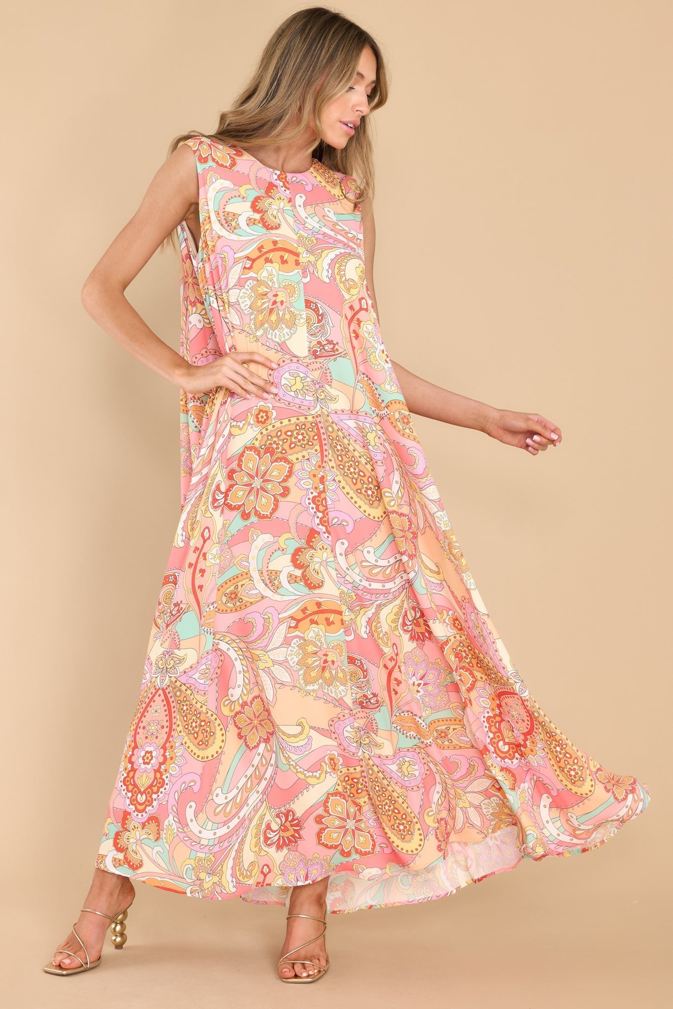 This multi-colored dress features a high round neckline, a sleeveless design, a keyhole cutout at the back of the neck with a button closure, and a loose, flowy silhouette.