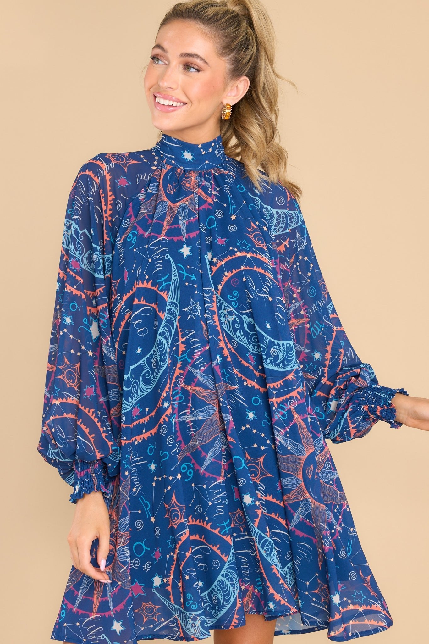 Front view of this dress that showcases the astrological print in shades of pink, orange, and blue.