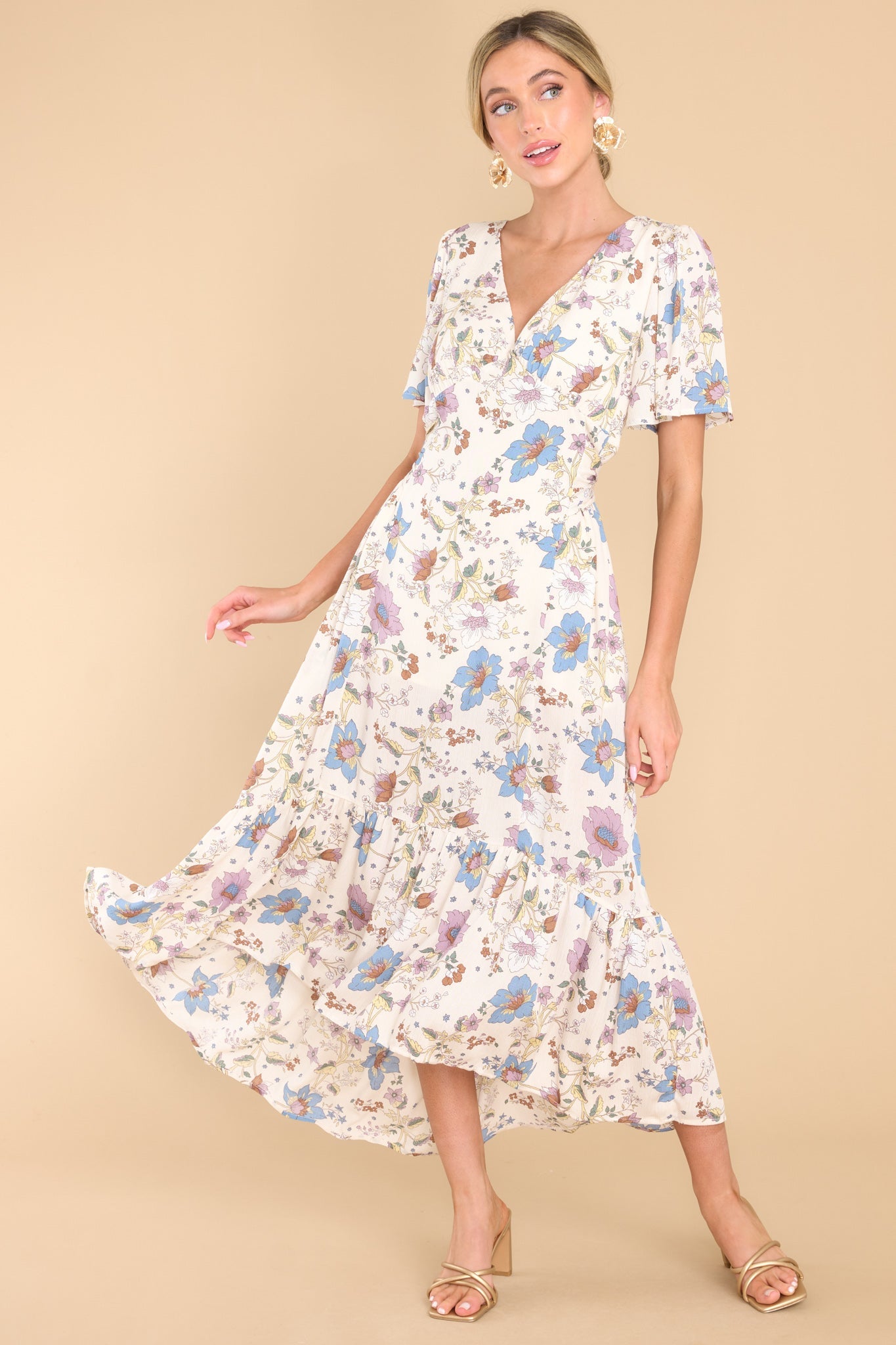 This ivory floral dress features a v-neckline, butterfly sleeves, a zipper in the back, a self-tie at the back of the waistline, and a flowy skirt.