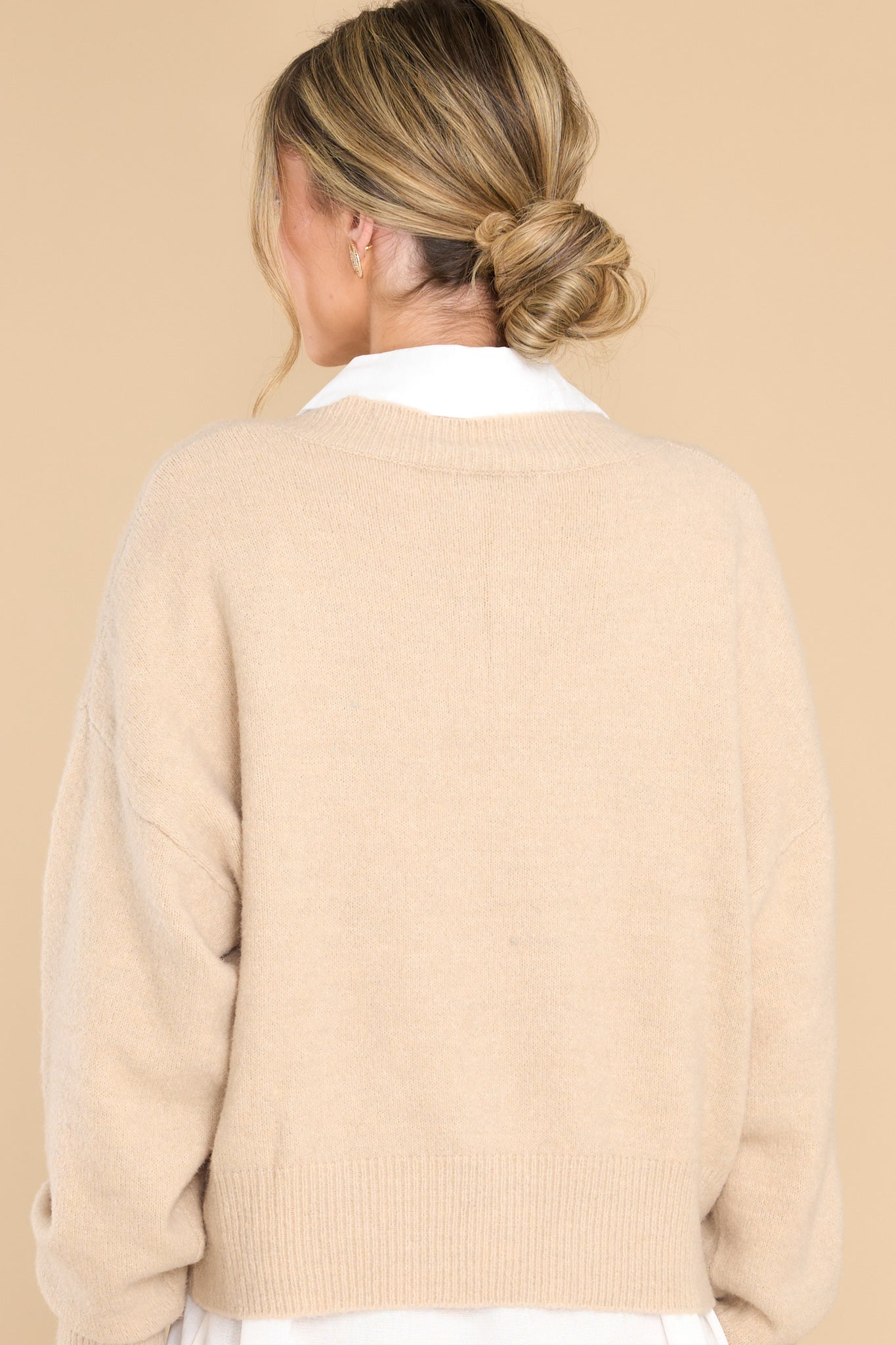 Back view of this sweater that features a v-cut neckline, long sleeves, and a ribbed waistband.