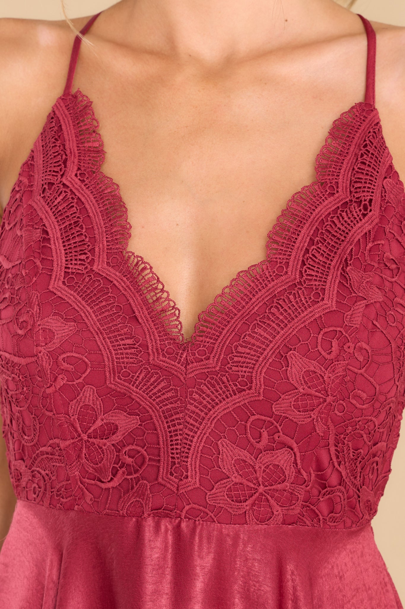 Close up view of this dress that features a v neck, lack detailing at the top, an open back, and a back zipper.