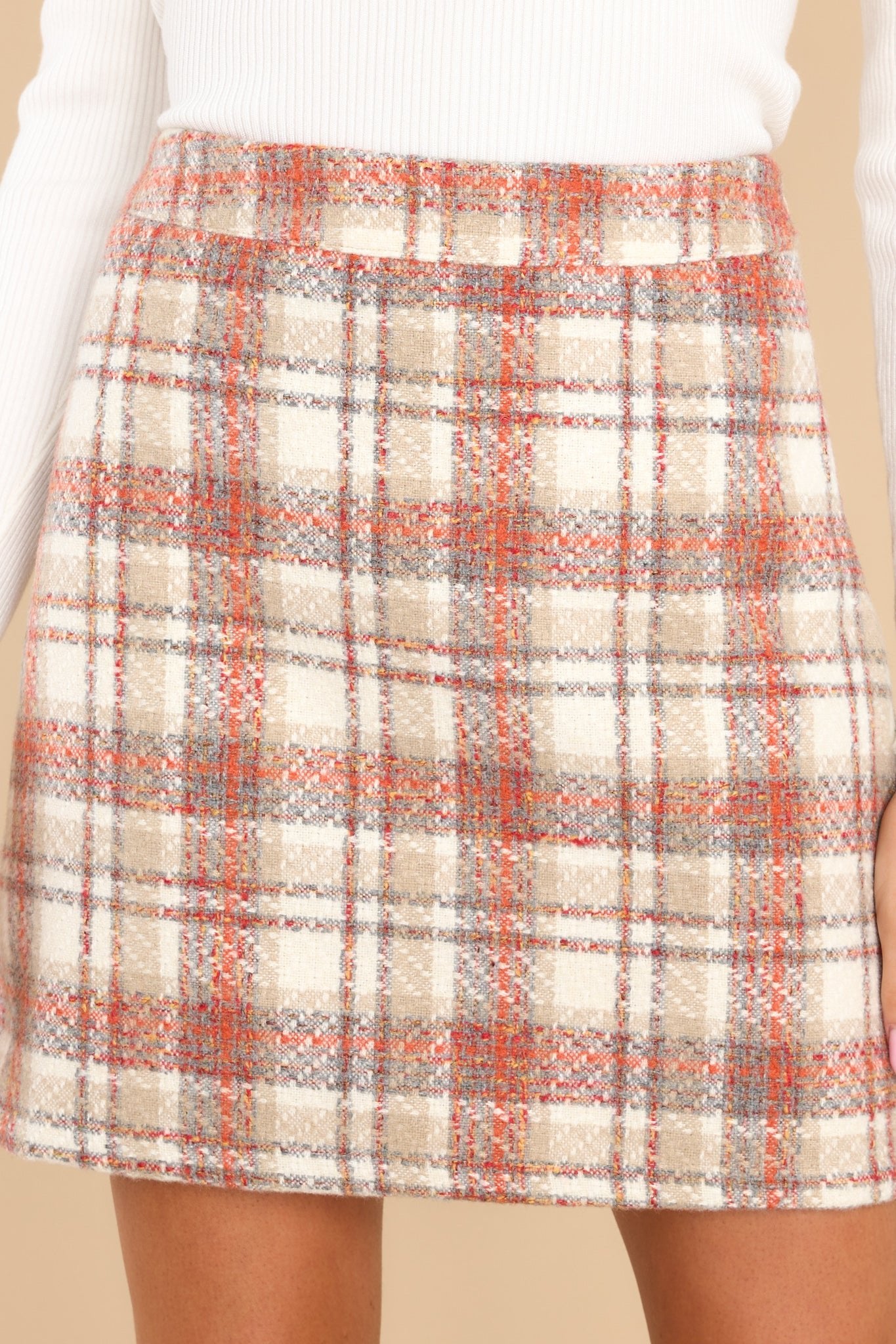 This beige skirt features a high waist, a plaid pattern, and a hidden zipper on the side.