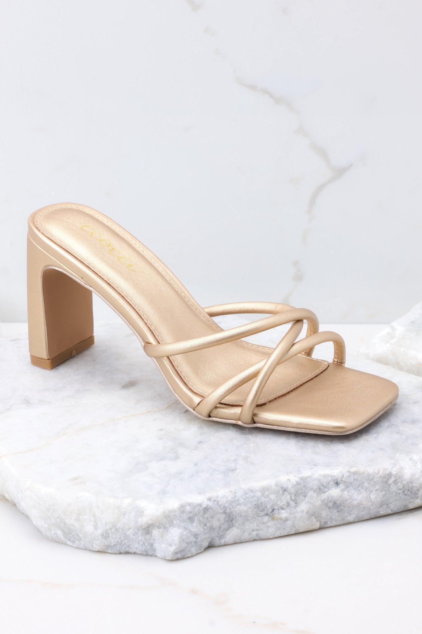 Outer-side view of  these sandals that feature a textured gold finish, three straps across the top of the foot, a flattened block heel, and light cushioning in the base.