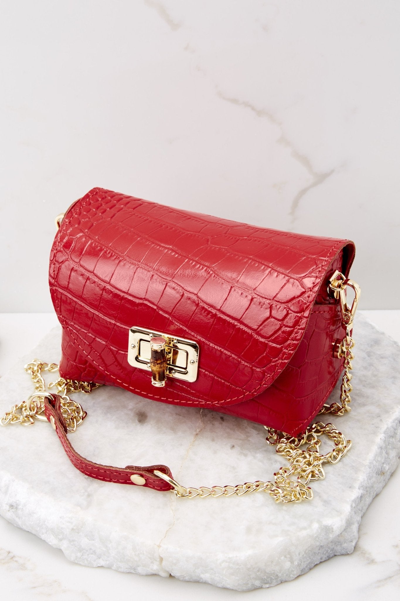 This red snake print bag features a leather body, gold-colored hardware, wooden turn-lock closure, detachable curb chain strap that drops 23".