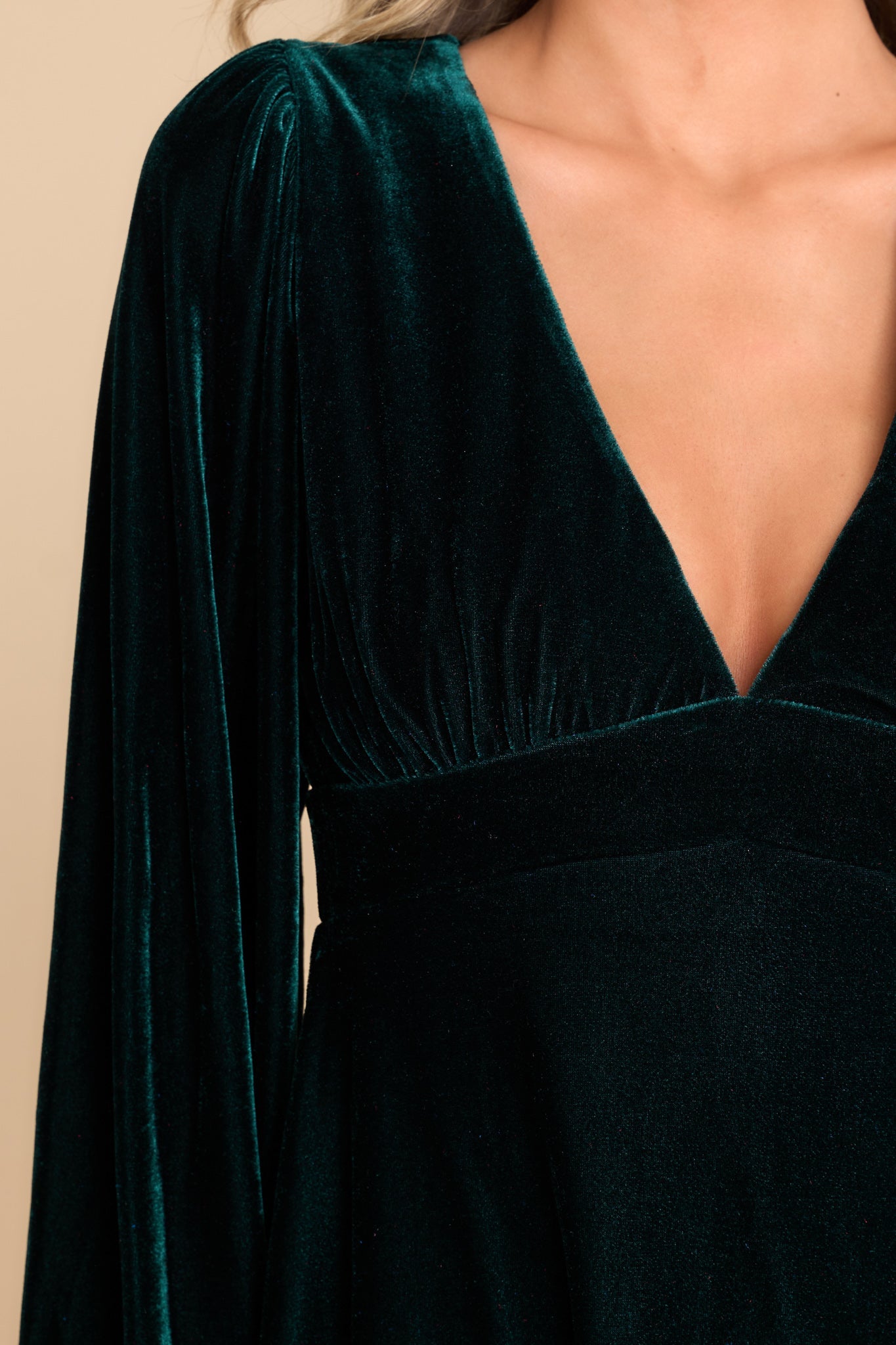 Close up view of this dress that features a plunge v-neckline, balloon elastic cuff sleeves, an A-line flared out bottom, and a back zipper hook and eye closure. 